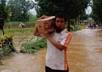 Relawan Terjang Banjir sambil Memikul Sembako untuk Bantuan